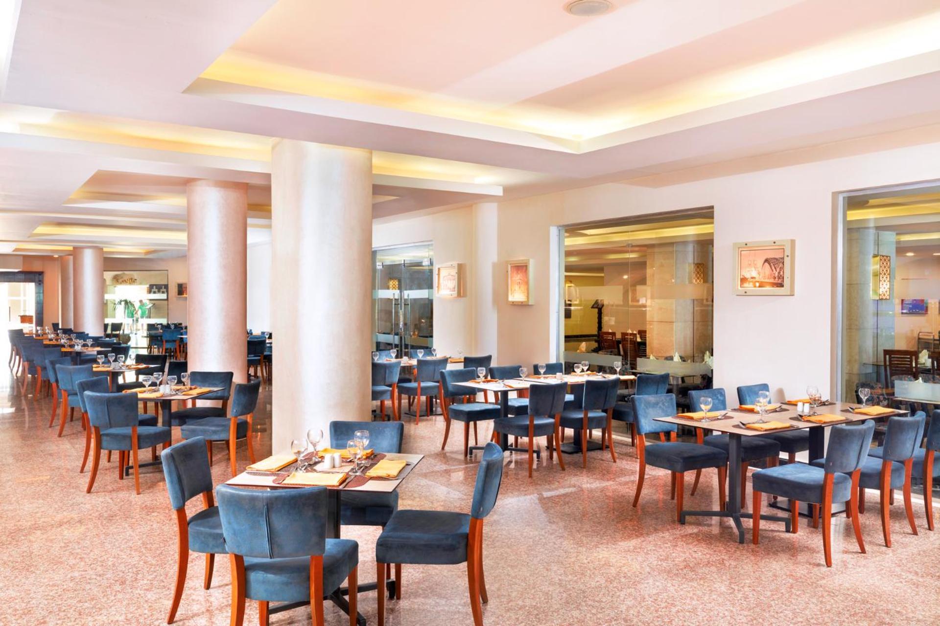 Hotel Pickalbatros Royal Moderna Sharm "Aqua Park" Exteriér fotografie The photo shows a spacious restaurant interior. It features several sets of tables and chairs arranged in a well-organized manner. The tables are dressed with placemats and utensils, indicating they are prepared for dining. The color scheme includes 